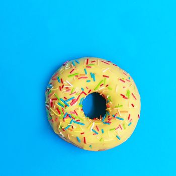 Bright yellow round Donuts with colorful sprinkles on a blue background