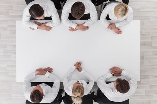 Business team sitting around white table, white copy space