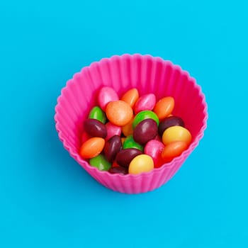Colorful candies in cupcake case on the blue background
