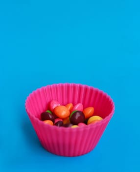 Colorful candies in cupcake case on the blue background