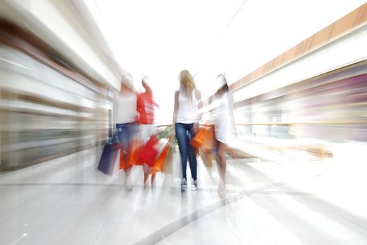 Women walking fast in shopping mall with bags