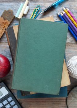 School stationery items on a wooden table with blank book cover 