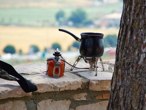 Making fresh hot coffee on a camping gas burner stove while hiking outdoors in nature