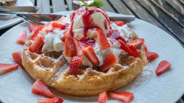 waffles with fresh strawberries and ice cream on white plate