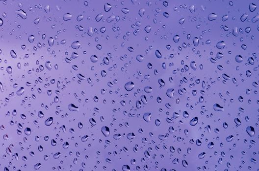 Water droplets on the glass with a colored background. Drops of water.