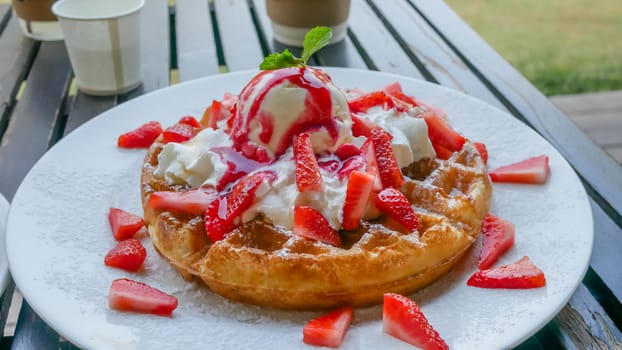waffles with fresh strawberries and ice cream on white plate
