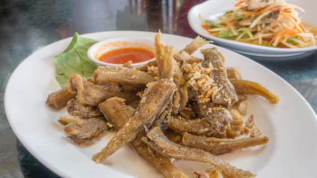 Fried fish topped with garlic served on dish with chili sauce