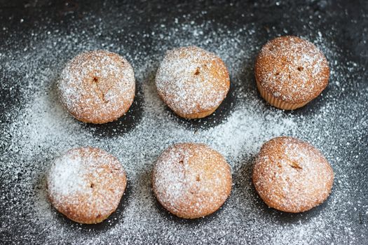 muffins in powdered sugar on a dark table