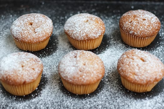 muffins in powdered sugar on a dark table