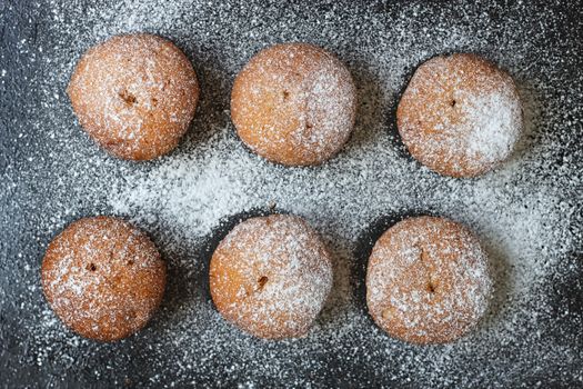 muffins in powdered sugar on a dark table