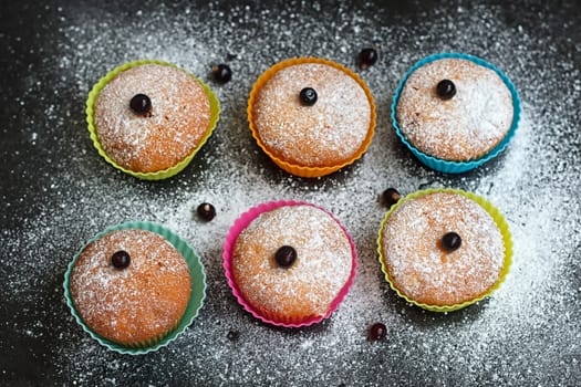 Muffins with black currant in silicone forms sprinkled with powdered sugar
