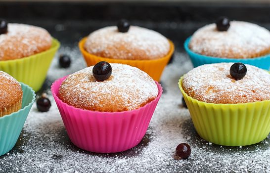 Muffins with black currant in silicone forms sprinkled with powdered sugar