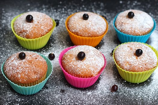 Muffins with black currant in silicone forms sprinkled with powdered sugar