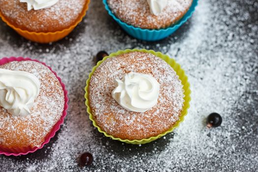 Muffins in colorful silicone forms with whipped cream