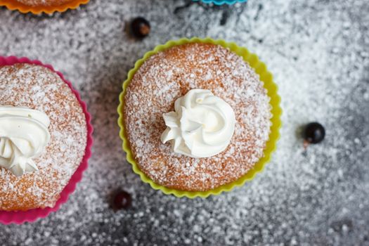 Muffins in colorful silicone forms with whipped cream