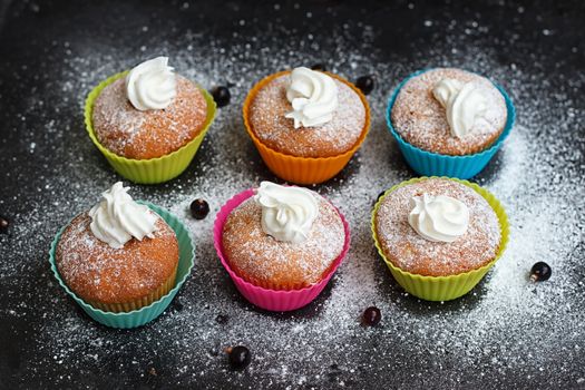Muffins in colorful silicone forms with whipped cream