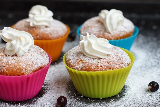 Muffins in colorful silicone forms with whipped cream