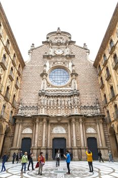 MONTSERRAT, SPAIN - MAY 10, 2016 :Tourists on the courtyard in front of Santa Maria de Montserrat Abbey, Catalonia. It  is a Benedictine abbey located on the mountain of Montserrat,  known for the cult statue of Virgin Mary.