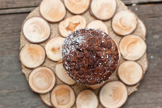 Chocolate muffin on a wooden stand on a light background