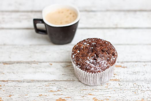 chocolate muffin and cup of coffee on the white wooden background