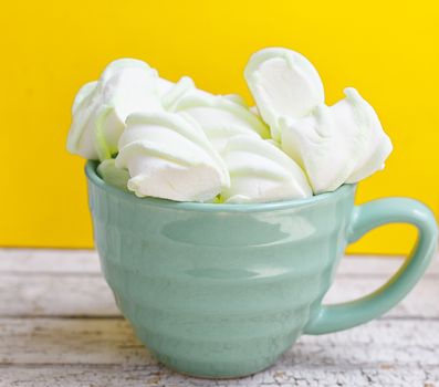 Peppermint large marshmallows in a large green cup on a yellow background