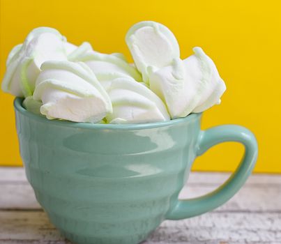 Peppermint large marshmallows in a large green cup on a yellow background