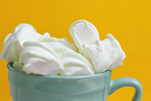 Peppermint large marshmallows in a large green cup on a yellow background