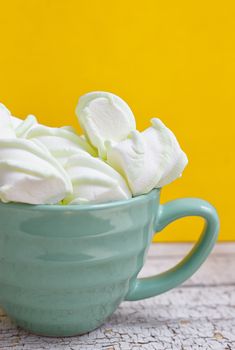 Peppermint large marshmallows in a large green cup on a yellow background