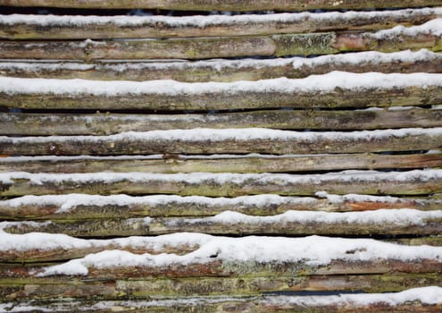 Snowy wooden pole fence wall in winter