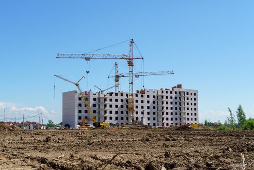 The construction of a multistory building. Construction cranes are on the building site