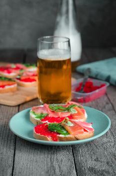 Sandwiches with seafood and beer in the background. Grey background, standing on old wooden surface.