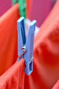 Clothespin on clothesline securing the red wet clothes. Red wet clothes drying on clothesline securing with clothespin.