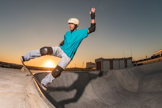 Skateboarder in a concrete pool at skatepark on a beatiful sunset.