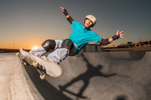 Skateboarder in a concrete pool at skatepark on a beatiful sunset.