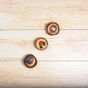 Pictured pastries on light wood background,above view,square photo.