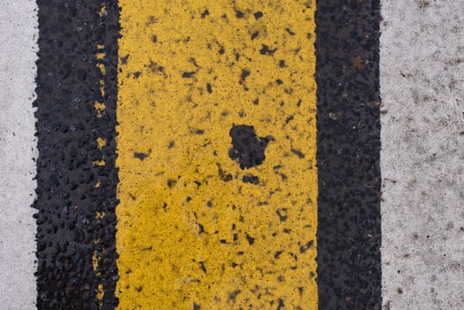 Asphalt highway texture with cracked white and yellow stripe.