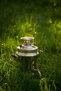 Rustic samovar on the fresh summer lawn. Copyspace.