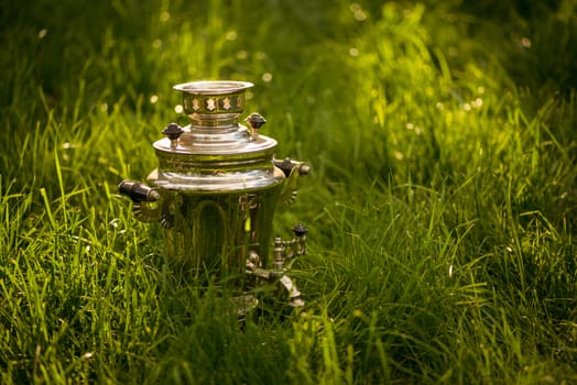 Rustic samovar on the fresh summer lawn. Copyspace.