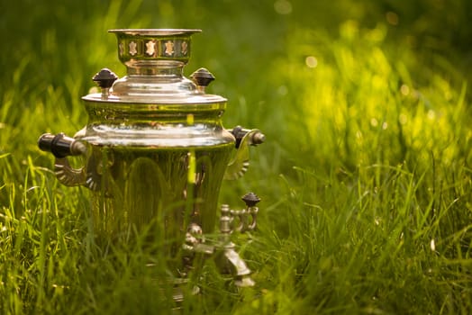 Rustic samovar on the fresh summer lawn. Copyspace.