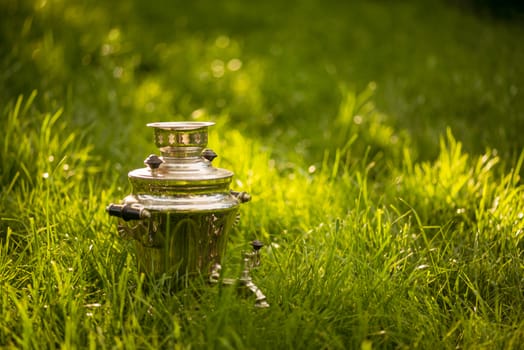 Rustic samovar on the fresh summer lawn. Copyspace.