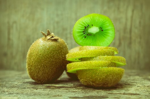 Close up slice of fresh kiwi fruit on old wood background, shallow depth of field (DOF) kiwi fruit in focus. Kiwi fruit is sweet and sour taste, nutritive value and high-fiber. Vintage picture style.