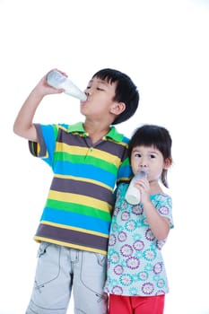 Asian children holding bottle of milk. Drinking milk for good health. Boy and girl drinking milk and hugging together, on white background. Studio shoot. The growth of children concept.