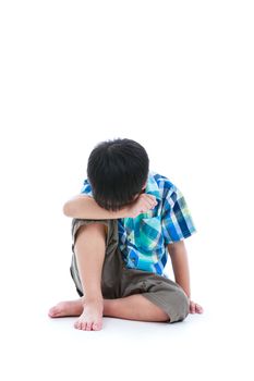 Little sad boy bare feet sitting on floor. Isolated on white background. Negative human emotions. Conceptual about children who lack warmth and affection, abandoned children. Free form copy space.