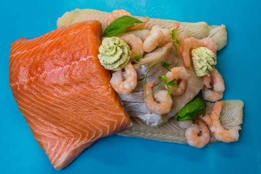 Various raw fish species as fillets like salmon, cod and shrimp.