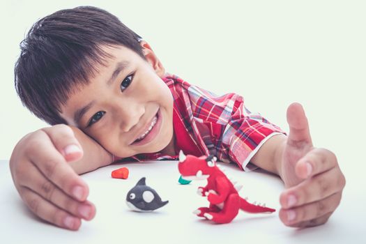 Asian boy create and show his toys from play dough, on white background. Strengthen the imagination of child. Vintage style. Cross process.