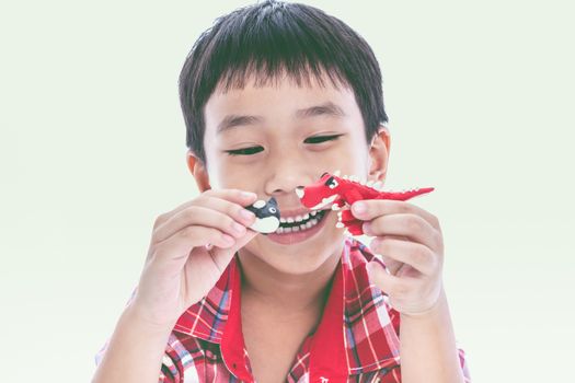 Asian boy create and show his toys from play dough, on white background. Strengthen the imagination of child. Vintage style. Cross process.