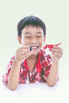 Asian boy create and play his toys from play dough, on white background. Strengthen the imagination of child. Vintage style. Cross process.