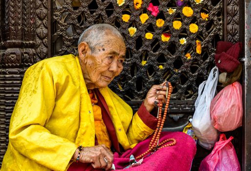 KATHMANDU, NEPAL - CIRCA MARCH 2013: Elderly Buddhist nun holding her prayer beads at Boudhanath stupa.