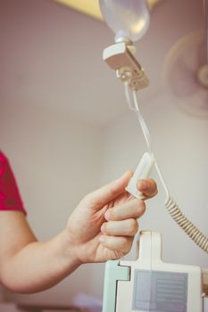 Nurse's hands regulation an intravenous (IV) drip in hospital room. Health care under medical observation. Vignette and vintage picture style.