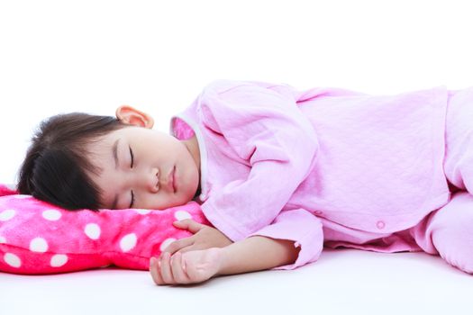 Healthy children concept. Little asian child sleeping peacefully. Adorable girl in pink pajamas taking a nap, on white background.